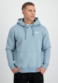 Sudadera azul claro con bolsillo tipo canguro, capucha con cordón y logo en el pecho. Presenta puños y dobladillo acanalados para un ajuste ceñido.