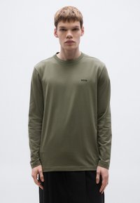 Μακρυμάνικη χακί μπλούζα από απαλό βαμβάκι με στρογγυλή λαιμόκοψη και μαύρο λογότυπο "BOSS" στο αριστερό στήθος. Μινιμαλιστικός σχεδιασμός.