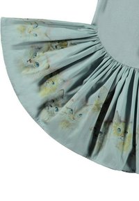 Ljusblå klänning med en skräddarsydd kjol som har akvarell-liknande illustrationer av katter. Slät tyg med mjuk textur, rundad dekolltage.