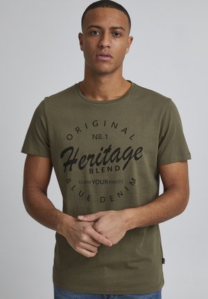 Oliven grøn kortærmet t-shirt med rund hals, prydet med et stort sort grafisk tryk i midten, der viser "Heritage Blend."