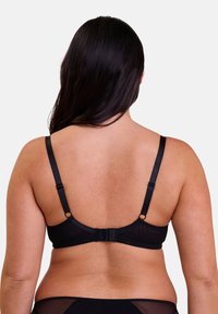 Sujetador negro con tirantes ajustables y cierre de gancho. Fabricado en tela suave con un panel de malla transparente en la parte posterior. Diseño simple, sin adornos.