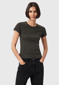 T-shirt corto verde scuro realizzato in cotone morbido, con un design aderente e collo rotondo, abbinato a pantaloni jeans neri a vita alta.