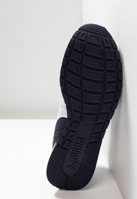 Chaussure de sport Nike avec une semelle extérieure en caoutchouc noire texturée, une tige synthétique blanche et marine, et un design élégant et moderne.