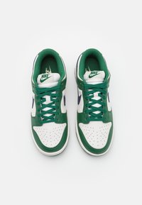 Gröna och vita Nike-sneakers med lågt skaft, lädermaterial, perforerad tåbox och kontrasterande marinblå swoosh.