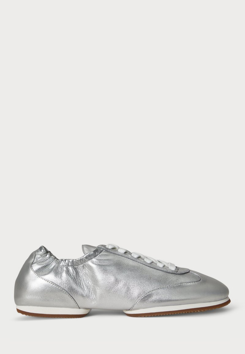 Metalne srebrne superge z gladko teksturo, zaobljenim prstom, gubanjem na vpetju in belimi vezalkami. Gumijast podplat z oprijemom.