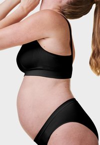 Czarny zestaw bielizny ciążowej składający się z biustonosza i majtek, wykonany z gładkiego, elastycznego materiału. Biustonosz ma cienkie ramiączka i bezszwowy krój dla wygody.