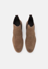 Bottines en daim marron avec une texture lisse, des panneaux latéraux élastiques et une languette au talon. Semelle plate et design à bout rond.