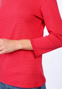 Langärmliges Oberteil mit roten und pinken Streifen, mit einem gewellten Ärmelabschluss, aus weichem Material, mit taillierter Passform und abgerundetem Saum.