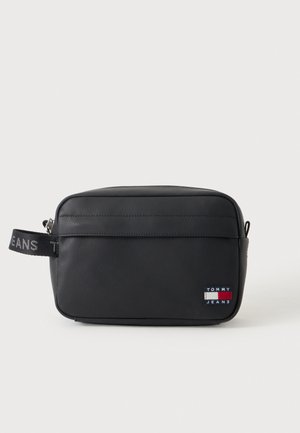 Bolsa de aseo rectangular negra con cremallera, asa lateral y pequeño parche con el logo de Tommy Jeans en la parte inferior derecha del frente.