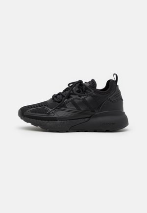 Baskets de sport noires avec dessus en mesh et synthétique, semelle épaisse et rembourrée, fermeture lacée et languette à tirer au talon.