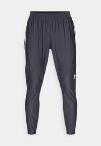 Sorte atletiske bukser i let, glat stof. Har en elastisk talje, tætsiddende ben og hvide sidelister. Logo nær kanten.