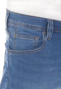 Jeans in denim di colore azzurro chiaro con cuciture arancioni. Presentano una tasca anteriore e passanti per la cintura. Il materiale sembra morbido con una leggera texture.