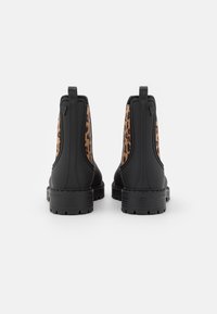 Black chelsea boots with leopard print side panels. Made of smooth leather with a textured sole and pull tab for easy wear.