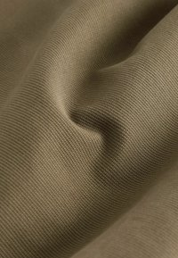 Tissu en vert olive sobre, présentant un tissage texturé avec des détails de motifs visibles et des plis doux.