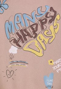 Text mit bunten Buchstaben, der "Viele glückliche Tage" sagt, umgeben von Kritzelzeichnungen von Blumen, Herzen und Phrasen wie "Mehr als Freunde, weniger als Liebhaber" auf rosa Stoff.