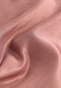 Tissu satin rose doux et froissé avec un lustre subtil et une texture de tissage fin en vue rapprochée.