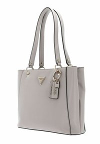 Sac fourre-tout gris clair avec une surface texturée, deux poignées, quincaillerie argentée et un logo proéminent. Il dispose d'un porte-clés décoratif et de bords cousus.