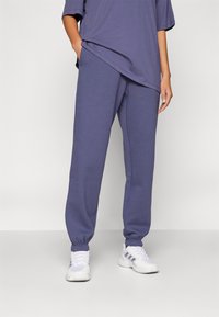 Pantalons de survêtement en tissu violet doux avec des chevilles resserrées, associés à un haut ample assorti. Comprend une taille élastique et des poches latérales.