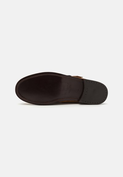 Suola di scarpa in pelle marrone con una finitura liscia, forma arrotondata e una cucitura a contrasto lungo il bordo. Presenta un marchio impresso e piccole perforazioni.