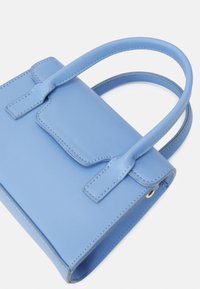 Světlomodrá kožená kabelka se strukturálním designem, vybavená uzávěrem na klopu, dvěma uchy a viditelnými švy.
