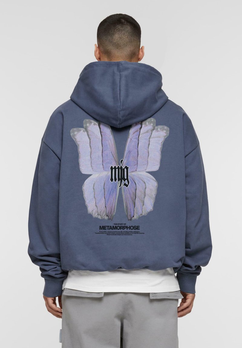 Blaues oversized Hoodie mit einem großen Schmetterlings-Graphic in Lila auf der Rückseite, mit Text darunter. Aus Baumwollmaterial, weiche Textur, gerippte Bündchen.