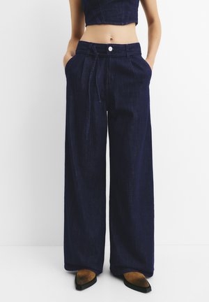 Wijd gevallen donkerdenim broek met een trekkoord in de taille en voorzakken, met een soepele textuur en klassieke knoopsluiting.