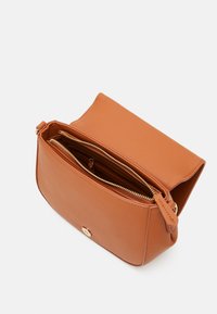 Borsa a tracolla in pelle marrone chiaro con chiusura a zip, tasche interne e un accento in hardware dorato. Texture liscia e forma rettangolare.