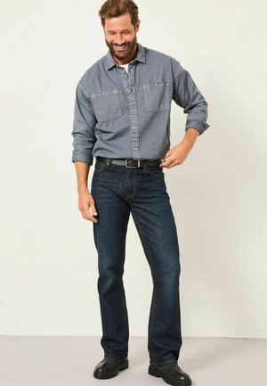 Dunkelblaue Denim-Jeans mit geradem Bein, kombiniert mit einem hellblauen Langarm-Hemd mit Knopfverschluss und zwei vorderen Taschen.