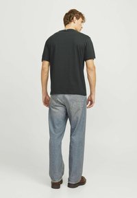 Sort kortærmet skjorte med en afslappet pasform, parret med lyseblå lige ben jeans. Begge beklædningsgenstande har enkle designs og bløde teksturer.