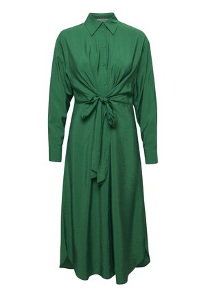 Groene jurk van gladde stof, met een knoopsluiting aan de voorkant, lange mouwen en een zelfstrikdetail in de taille voor een getailleerd silhouet.