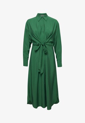 Groene jurk van gladde stof, met een knoopsluiting aan de voorkant, lange mouwen en een zelfstrikdetail in de taille voor een getailleerd silhouet.