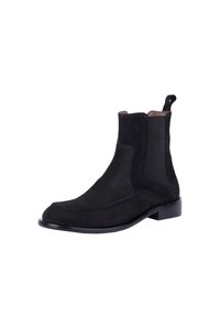 Stivaletti in suede neri con pannelli elastici laterali, punta rotonda e tacco basso a blocco. Presentano una linguetta sul retro per indossarli facilmente.