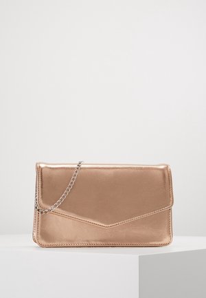Pochette métallique en or rose avec bandoulière chaîne argentée, forme rectangulaire, et fermeture à rabat style enveloppe sur un piédestal blanc.