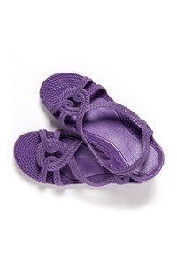 Sandalias de cuerda trenzada morada con un diseño anudado sobre los dedos y una correa ajustable en el tobillo sobre un fondo blanco.