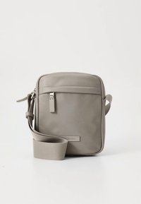 Grijze schoudertas van glad materiaal met een voorkant ritsvak, verstelbare riem en subtiele branding aan de voorkant.