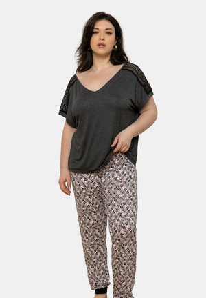 Haut gris à col en V avec des accents en dentelle sur les épaules, associé à un pantalon ample présentant un motif de feuilles florales dans des tons de rose et de noir.
