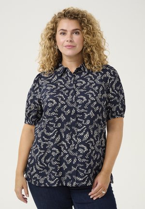 Námořnická blůza s krátkým rukávem a bílým abstraktním vzorem, s límečkem, na knoflíky vpředu a jemně nařasenými rukávy. Měkká tkanina, uvolněný střih.