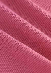 Tissu rose texturé avec des nervures étroites, présentant une surface douce et uniforme avec des variations subtiles de couleur et de motif.
