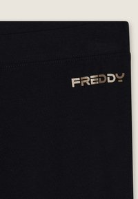 Leggings neri in cotone con una texture liscia e il logo dorato "FREDDY" ben visibile sulla vita. Design semplice e minimalista.