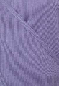 Tejido de color púrpura con nervaduras y un acabado texturizado, que presenta una línea de diseño diagonal. El material suave le da un aspecto elástico.