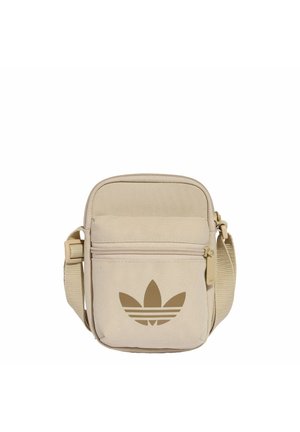 Béžová crossbody taška Adidas s nastavitelným popruhem, přední kapsou na zip a velkým hnědým logem Adidas Trefoil.