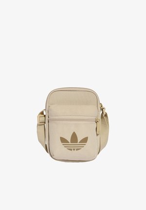 Béžová crossbody taška Adidas s nastavitelným popruhem, přední kapsou na zip a velkým hnědým logem Adidas Trefoil.