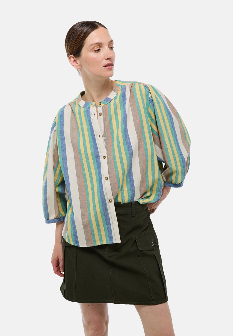 Chemise rayée légère à encolure ronde, avec des manches courtes bouffantes et des boutons sur le devant. Les couleurs comprennent le bleu, le jaune, le vert et le beige.