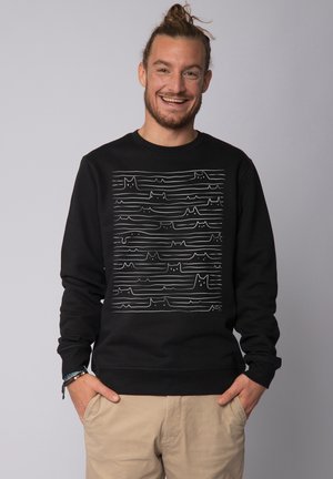 Black sweatshirt featuring a line art design with cat silhouettes on a horizontal wave pattern. Made from soft fabric, crew neck style.