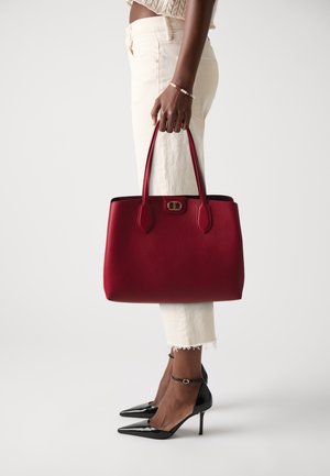 Red leather tote bag with a structured shape, dual handles, and a gold-tone clasp. Features a textured surface and solid color design.