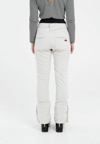 Witte broek met een getailleerd ontwerp, voorzien van ritssluitingen bij de enkels en achterzakken. Gestyled met een geruite zwarte top.