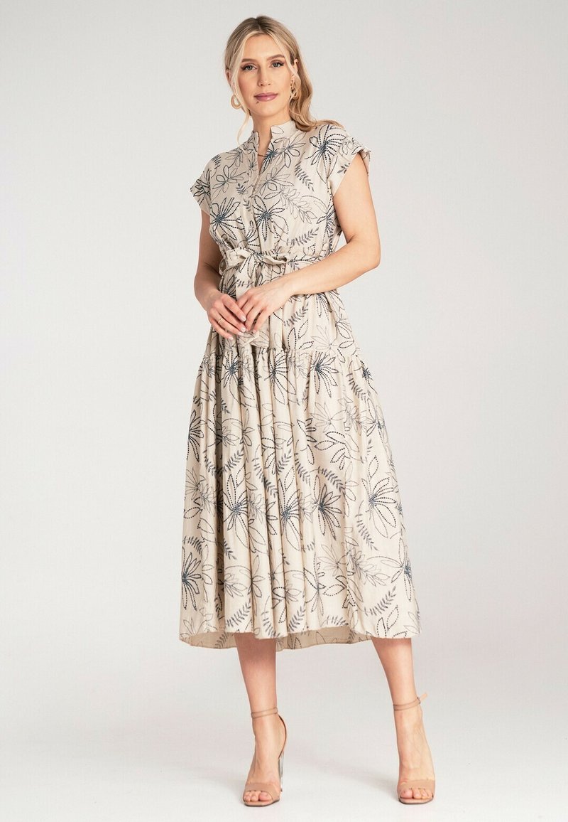 Helles beige Kleid mit blauen und schwarzen floralem Muster, kurzen Ärmeln, Knopfverschluss und tailliertem Schnitt, mit einem gestuften Rock.