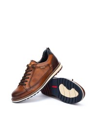 Zapatillas de cuero marrón con diseño de cordones, suelas de goma con textura antideslizante y detalles en contraste en el talón y la lengüeta.