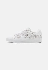 Zapatillas blancas con bordado floral en gris claro, con una parte superior de cuero suave, puntera redonda y una suela de goma texturizada.