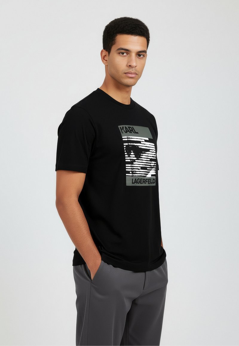 Musta puuvillainen t-paita, jossa on edessä kontrastivärinen "Karl Lagerfeld" -grafiikka. Lyhyet hihat ja pyöreä pääntie.
